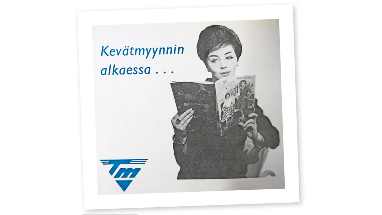 Vanha mainoskuva, jossa nainen lukee mainoslehtistä, vieressä teksti: Kevätmyynnin alkaessa.