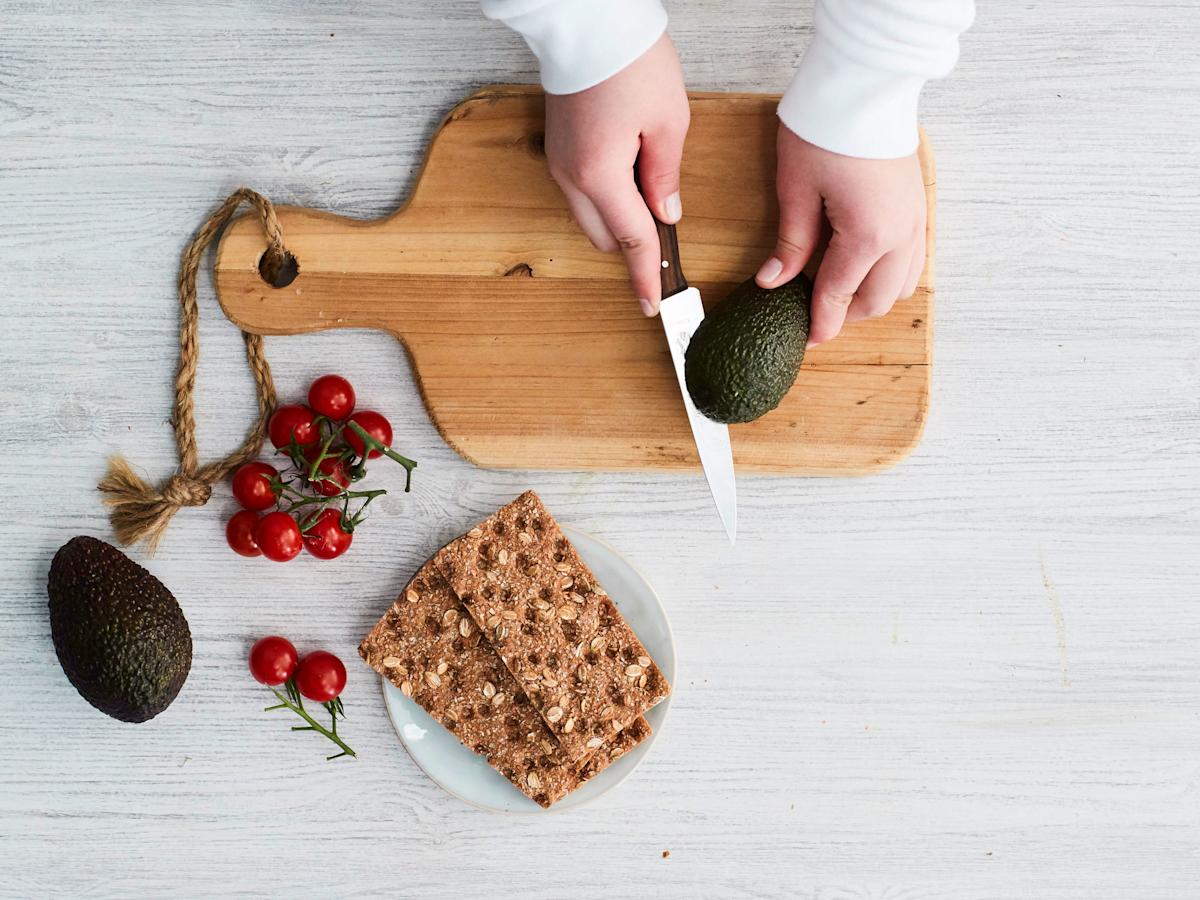 Leikkaa avokado halki niin, että veitsen terä on keskellä olevaa kiveä vasten. Tartu avokadon puolikkaisiin molemmilla käsillä ja käännä, niin puolikkaat irtoavat toisistaan.