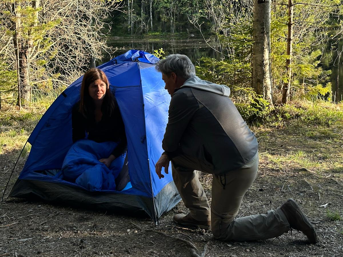 Mirka on pystyttänyt Nuuksioon lammen rannalle teltan ja Jukka ohjeistaa perusasioissa.