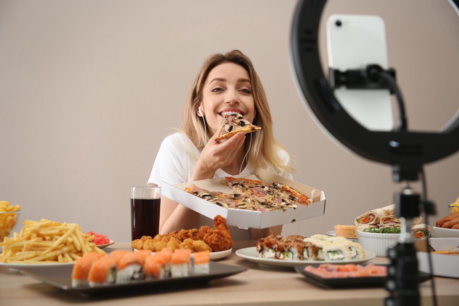 Nainen kuvaa mukbang-videota pöydän ääressä