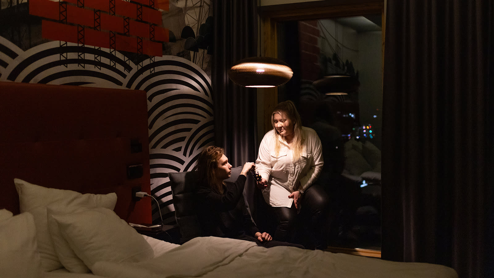 Jere Saari ja Pinja Saarenpää istumassa hotellihuoneen ikkunan äärellä.