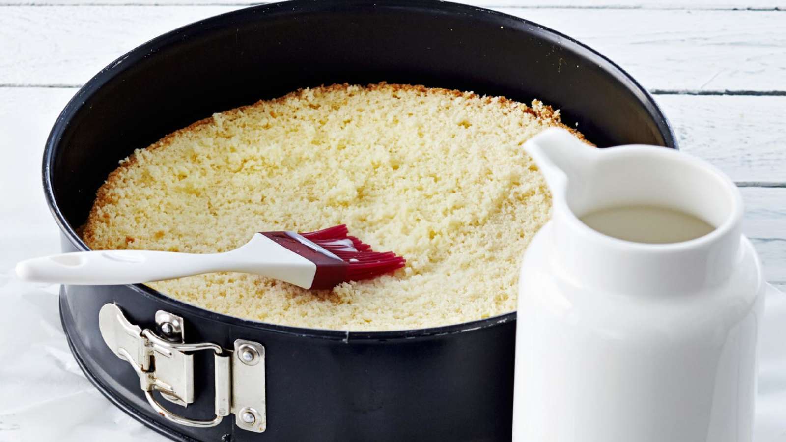 Nosta alin kakkulevy leivinpaperilla vuorattuun kakkuvuokaan. Kostuta kakkulevy maidolla.