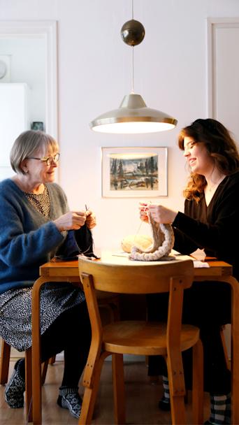 Michelle Ålander ja hänen mummonsa Kaarina Lindqvist neulovat pöydän ääressä.
