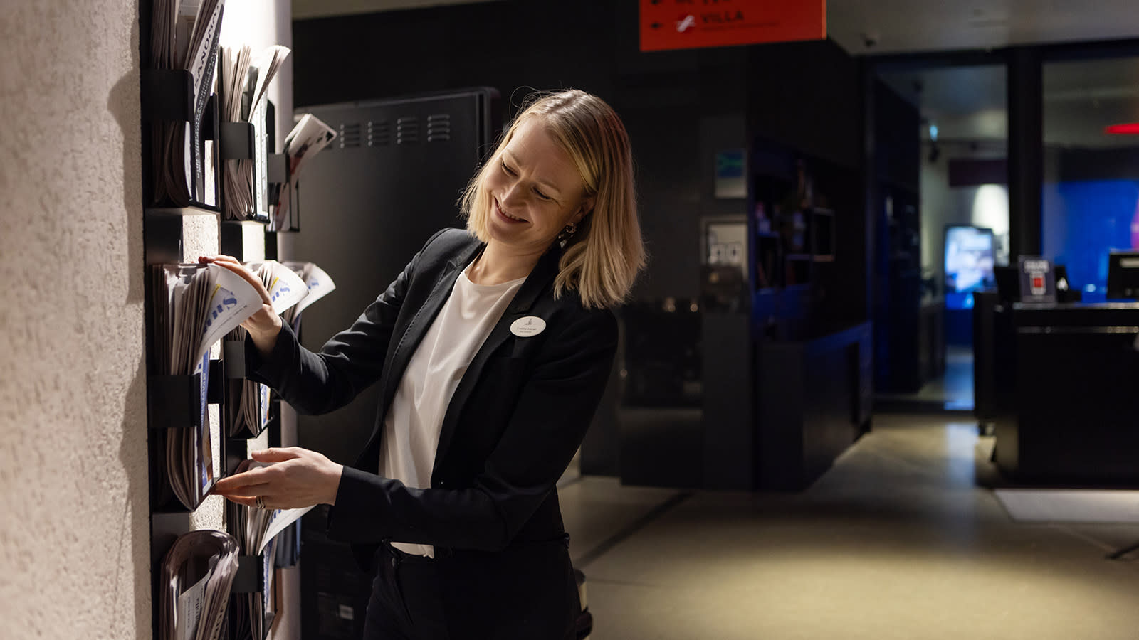 Eveliina Jokinen järjestelee seinään kiinnitettyä lehtitelinettä.