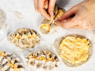 Sudi jauhot pois. Levitä pari ruokalusikallista täytettä kuorille. Käännä reunat täytteen päälle ja rypytä molemmin etusormin yhtä aikaa keskeltä alkaen kärkeä kohden, käännä ja rypytä loppuun.