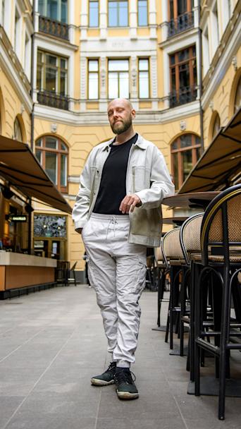 Valkoisiin pukeutunut mies seisoo sisäpihalla.