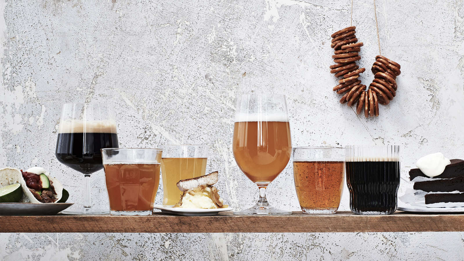 Kuusi erilaista olutta laseissa sekä oluisiin sopivia ruokia.