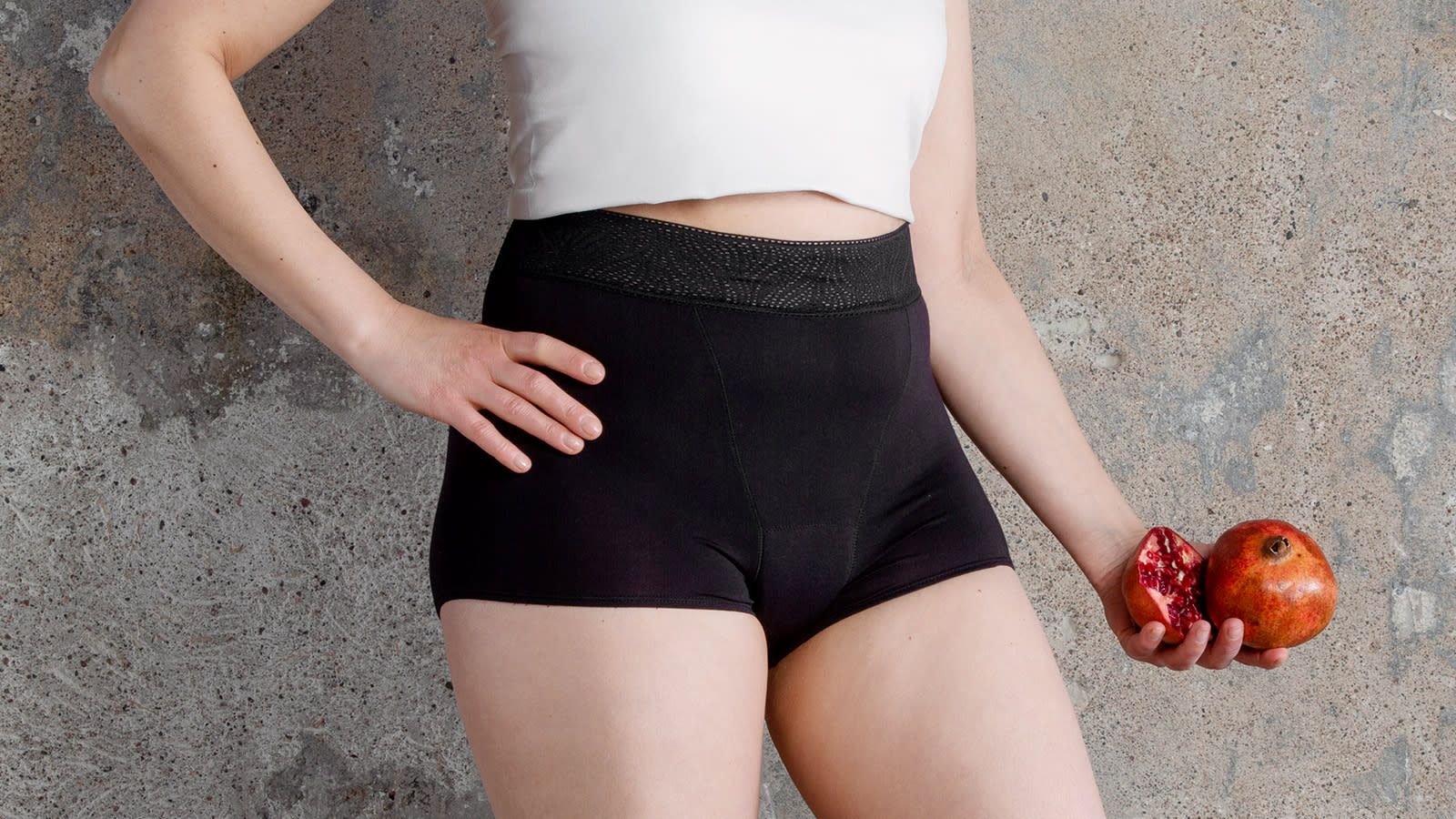 Sloggi short-malliset kuukautisalushousut mallin päällä, somisteena punainen granaattiomena.