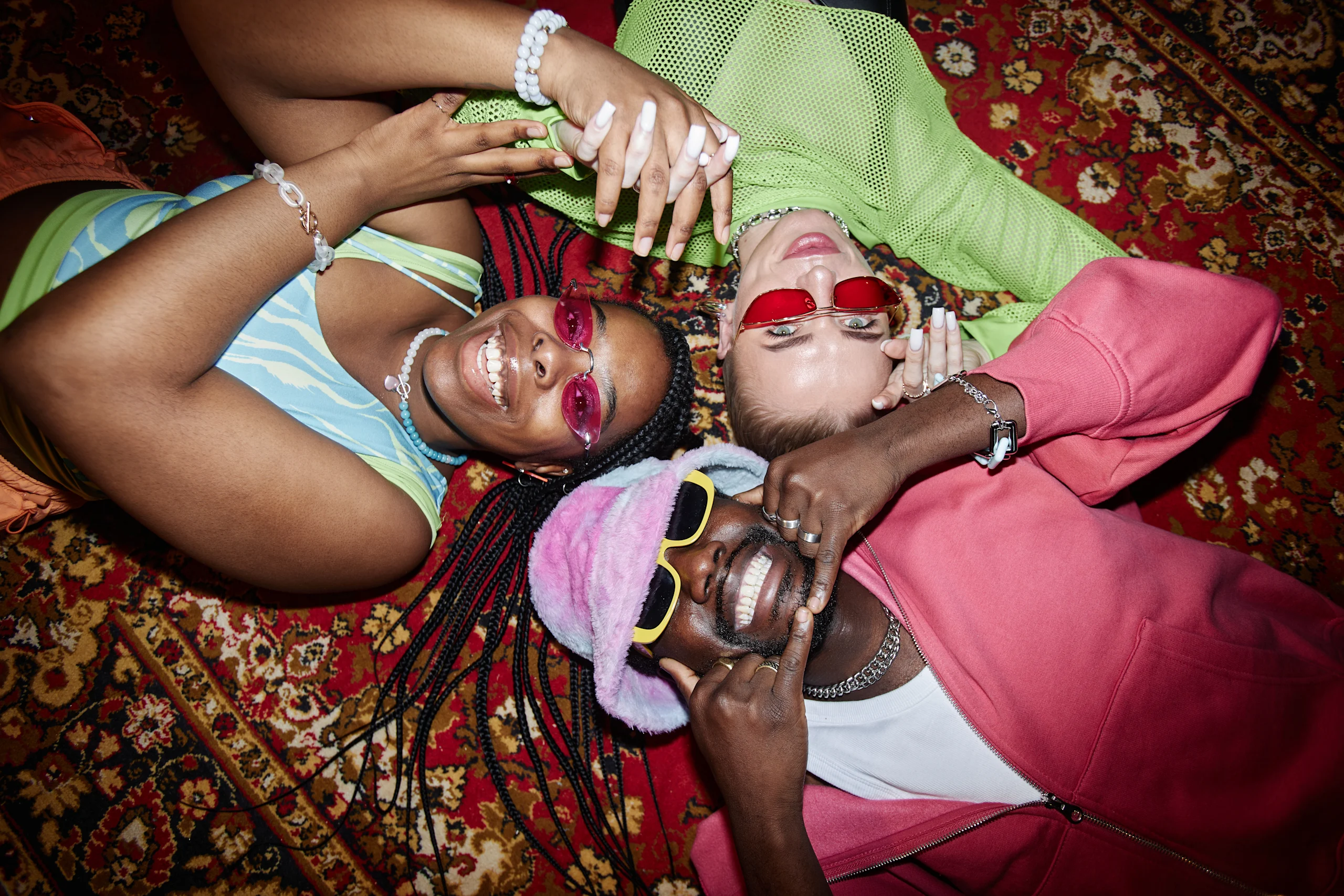 Y2K-tyyliin pukeutuneita nuoria makaa lattialla iloisena