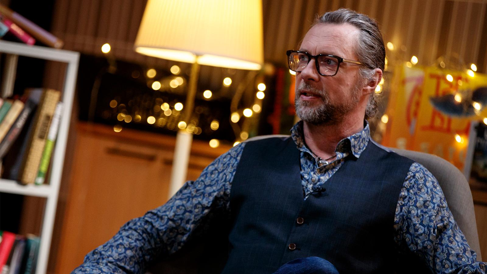 Antti Reini istuu tuolilla Ässäkeskuksen studiossa haastateltavana