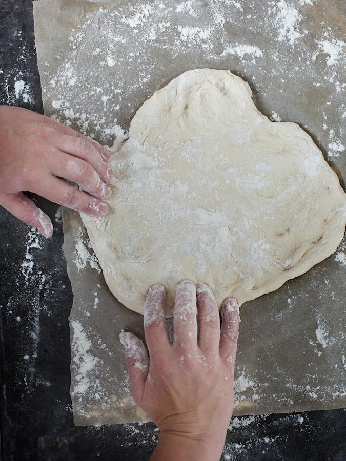 3\. Säädä uuni 250 asteeseen. Muotoile pohja jauhotetulla alustalla käsin, älä kauli. Tee pellillinen tai pienempiä pizzoja. Painele pohja aitoon napolilaiseen tyyliin taikinapalan keskeltä kohti reunoja, korkeintaan kolmen millin paksuiseksi.