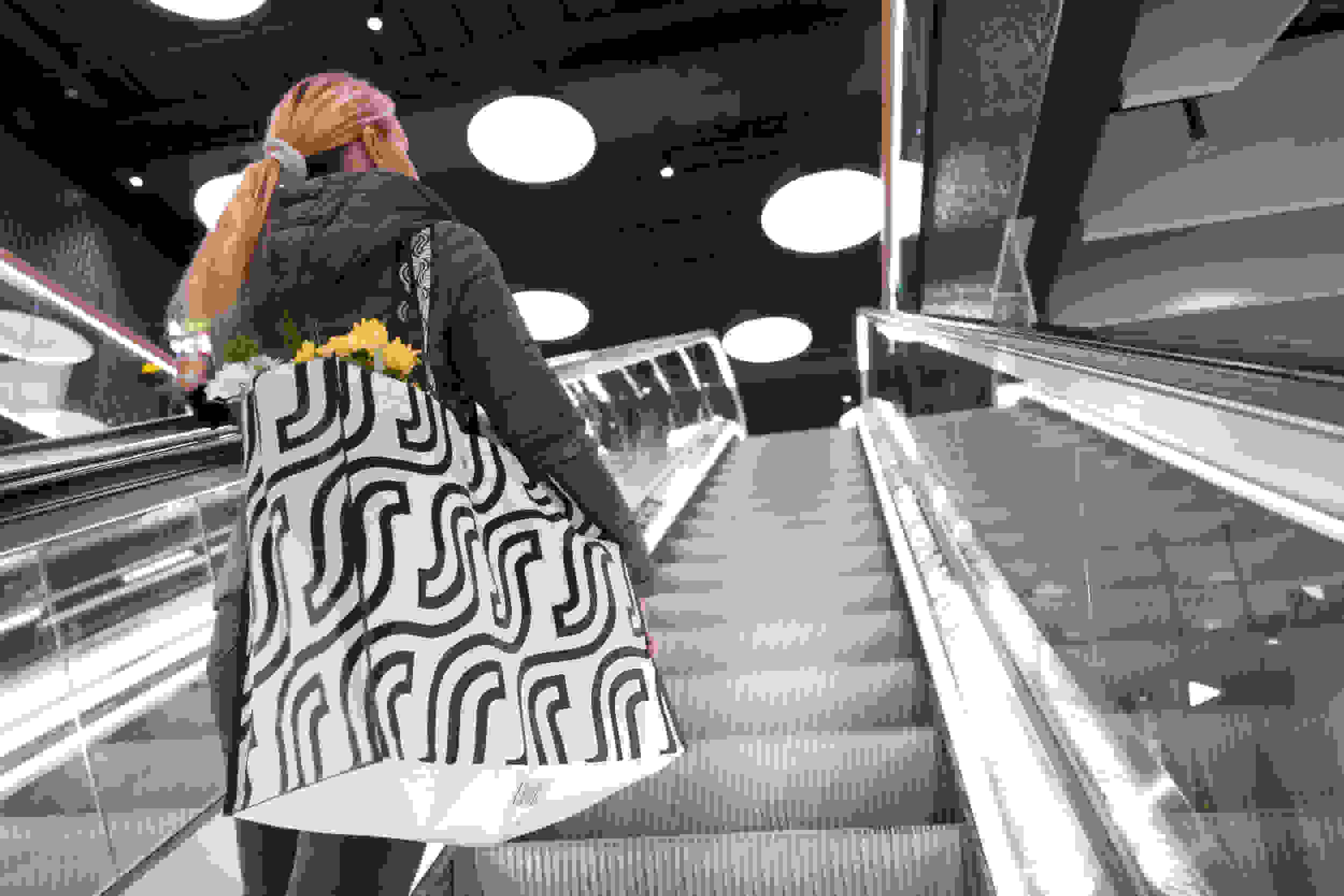 Nainen S-ryhmän kestokassin kanssa liukuportaissa