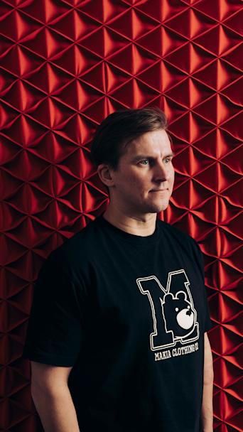 Makian perustaja Joni Malmi poseeraa punaisen seinän edessä.