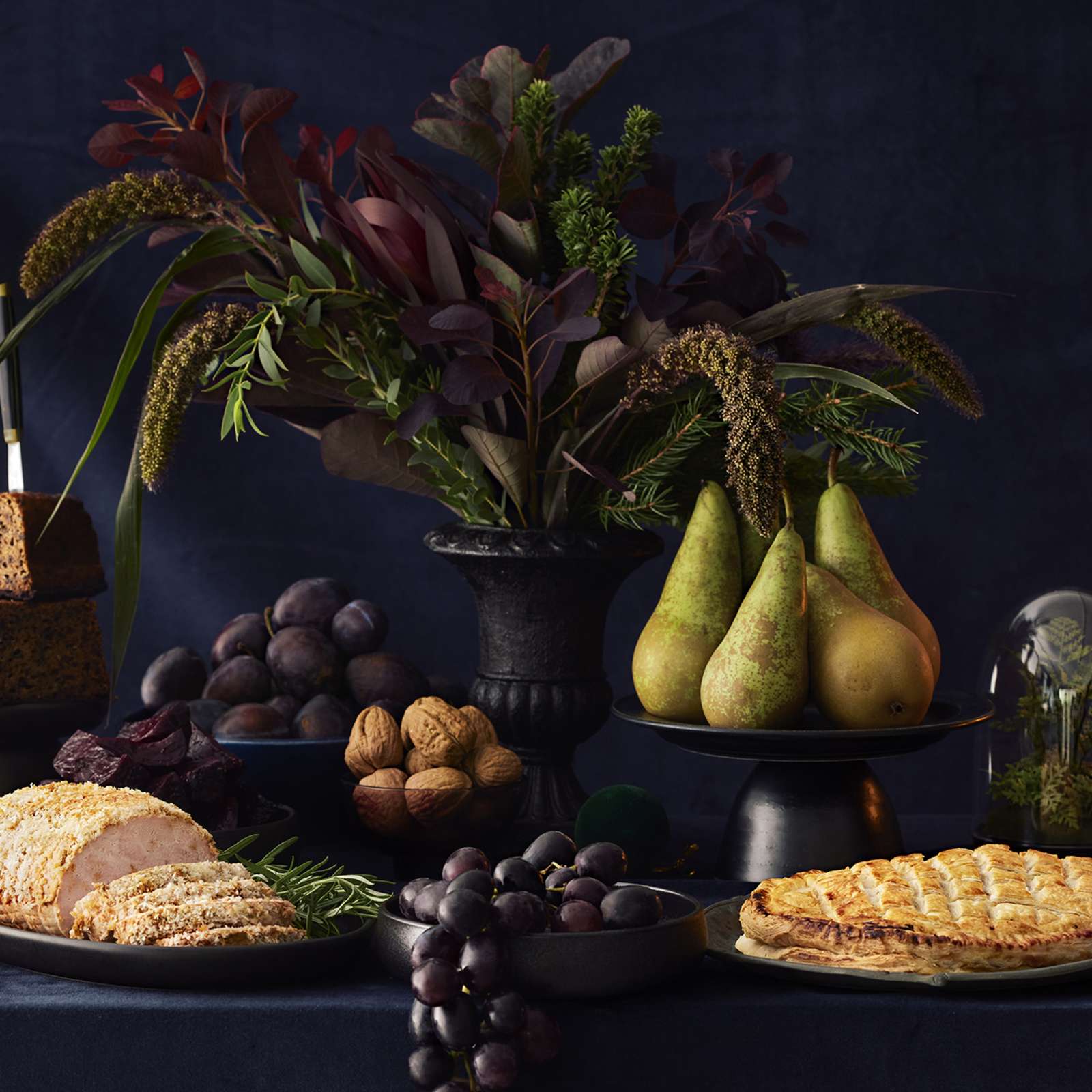 Jouluinen kattaus, jossa kalkkunarulla, vegaaninen Wellington, saaristolaisleipä, hedelmiä, pähkinöitä, juustoja, kynttilöitä ja kukka-asetelma