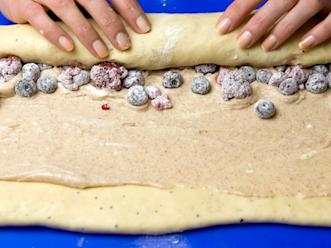 Lisää tuorejuustokerroksen päälle jäinen marja-perunajauhoseos. Rullaa taikina kääretortun tapaan tiiviiksi rullaksi. Leikkaa rulla terävällä veitsellä melko leveiksi paloiksi.