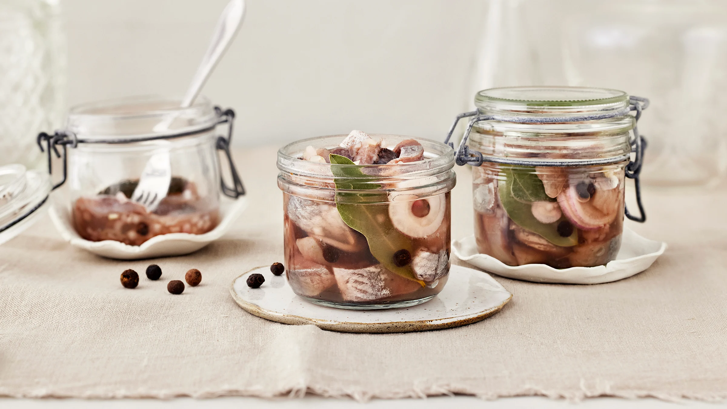 Ranskalaista sipulisiliiä kolmessa lasipurkissa, joista yhdessä haarukka. Purkkien alla vaaleat lautaset. Pöydällä pippureita ja vaalea liina.