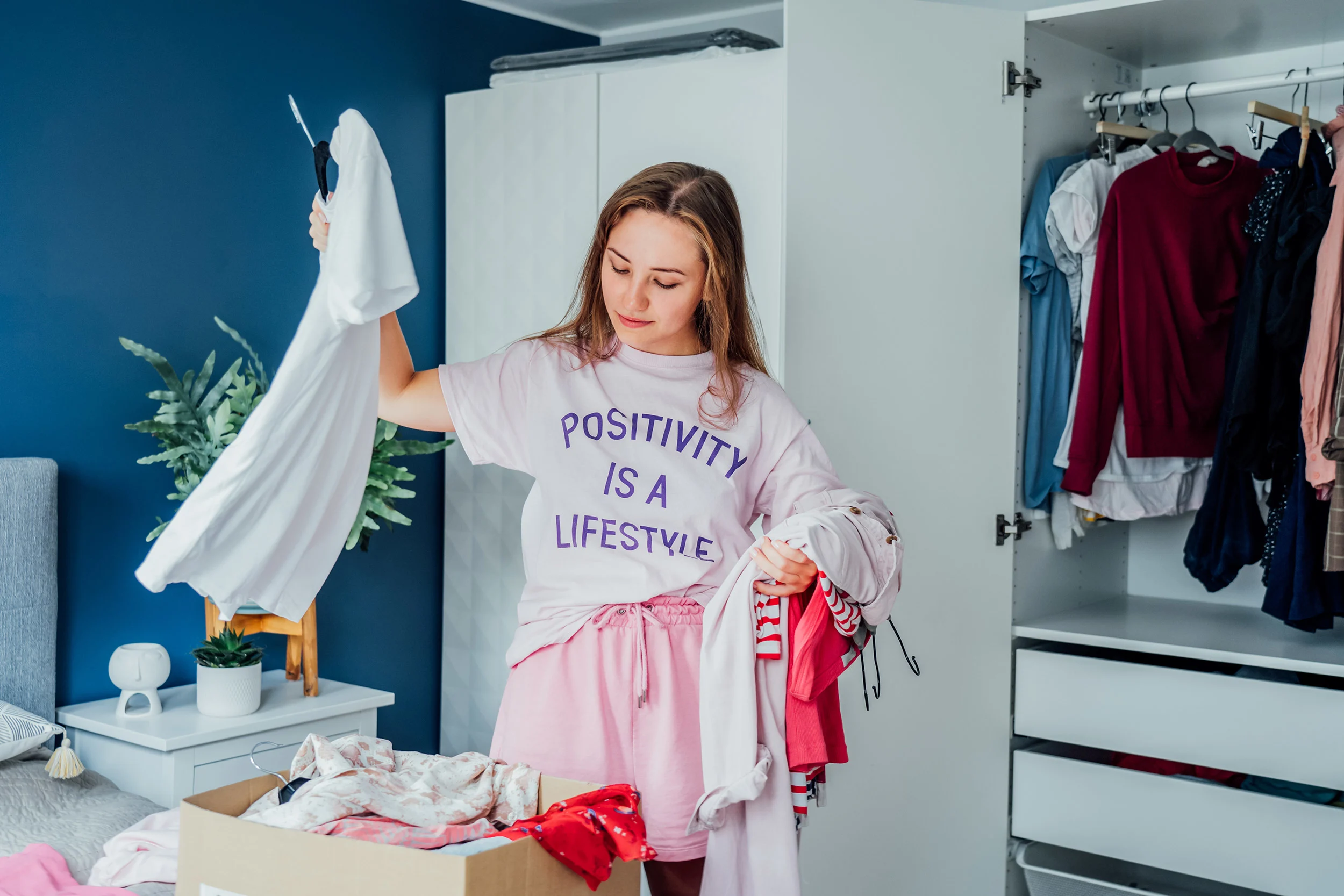 Nainen valitsee vaatekaapistaan vaatteita kierrätykseen. 