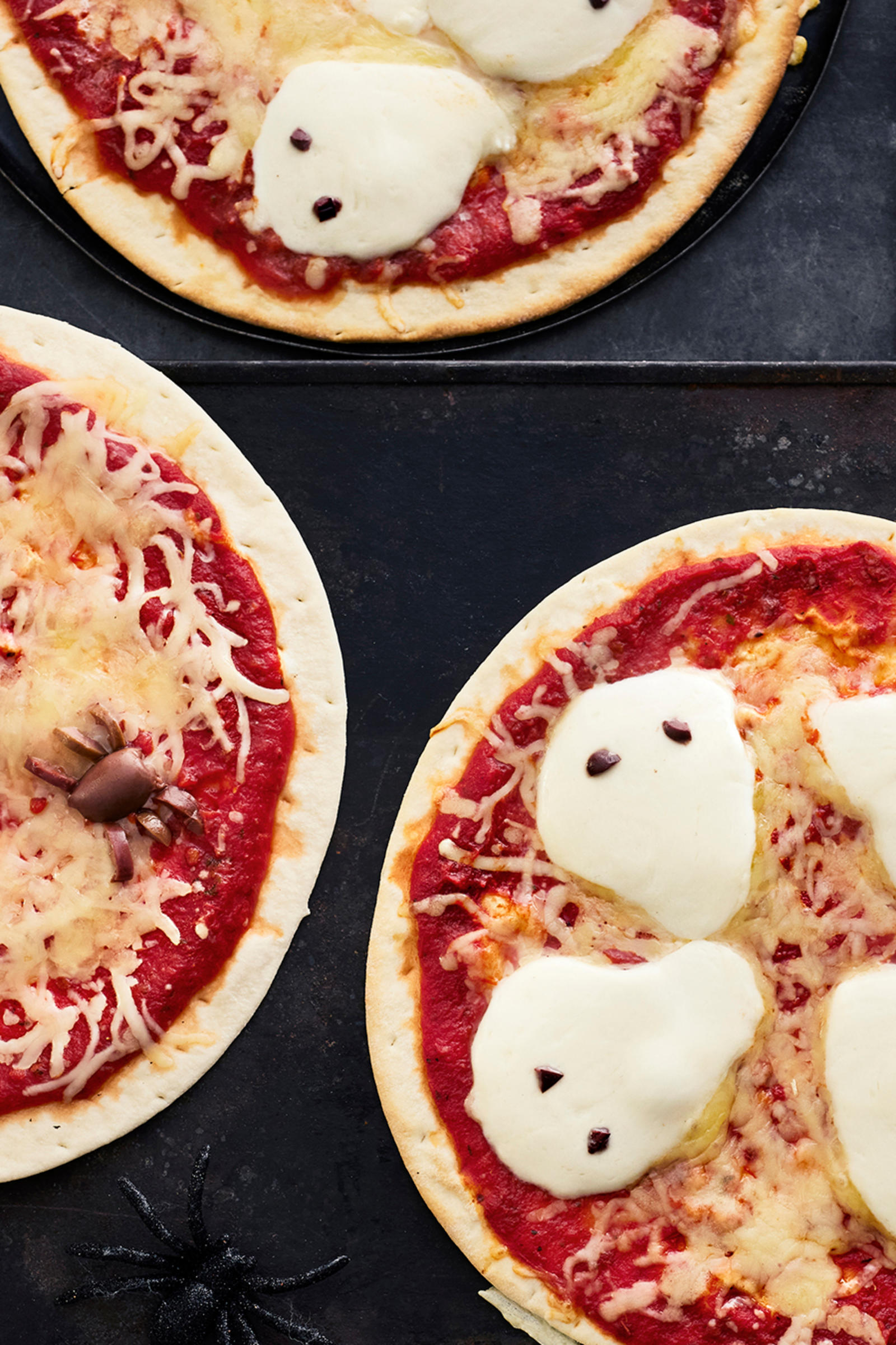 Halloweeniin sopivia pizzoja, joiden päälle asetellut oliivit muistuttavat hämähäkkejä ja mozzarellaviipaleet haamuja.