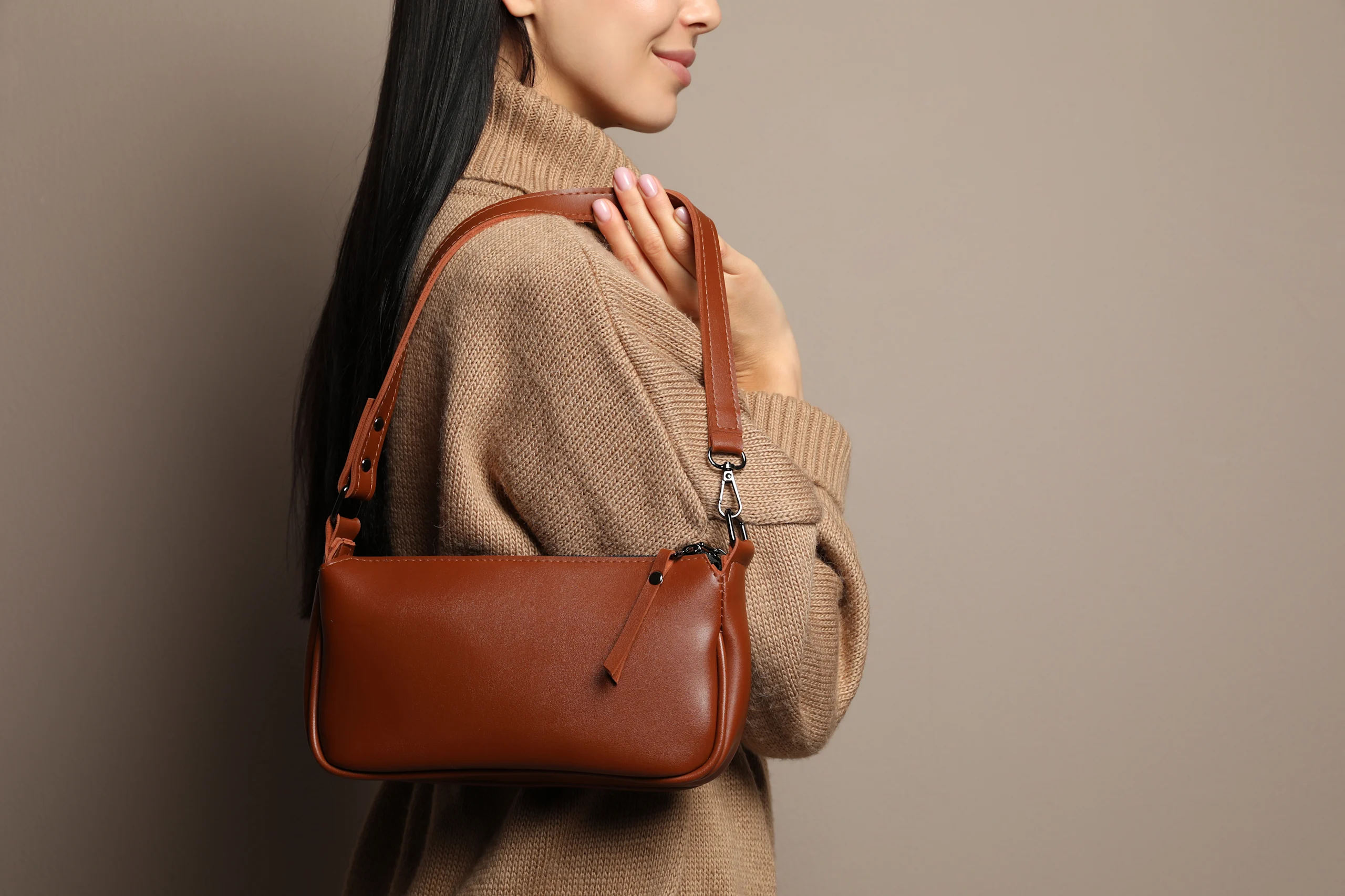 Nainen pitelee olallaan ruskeaa käsilaukkua