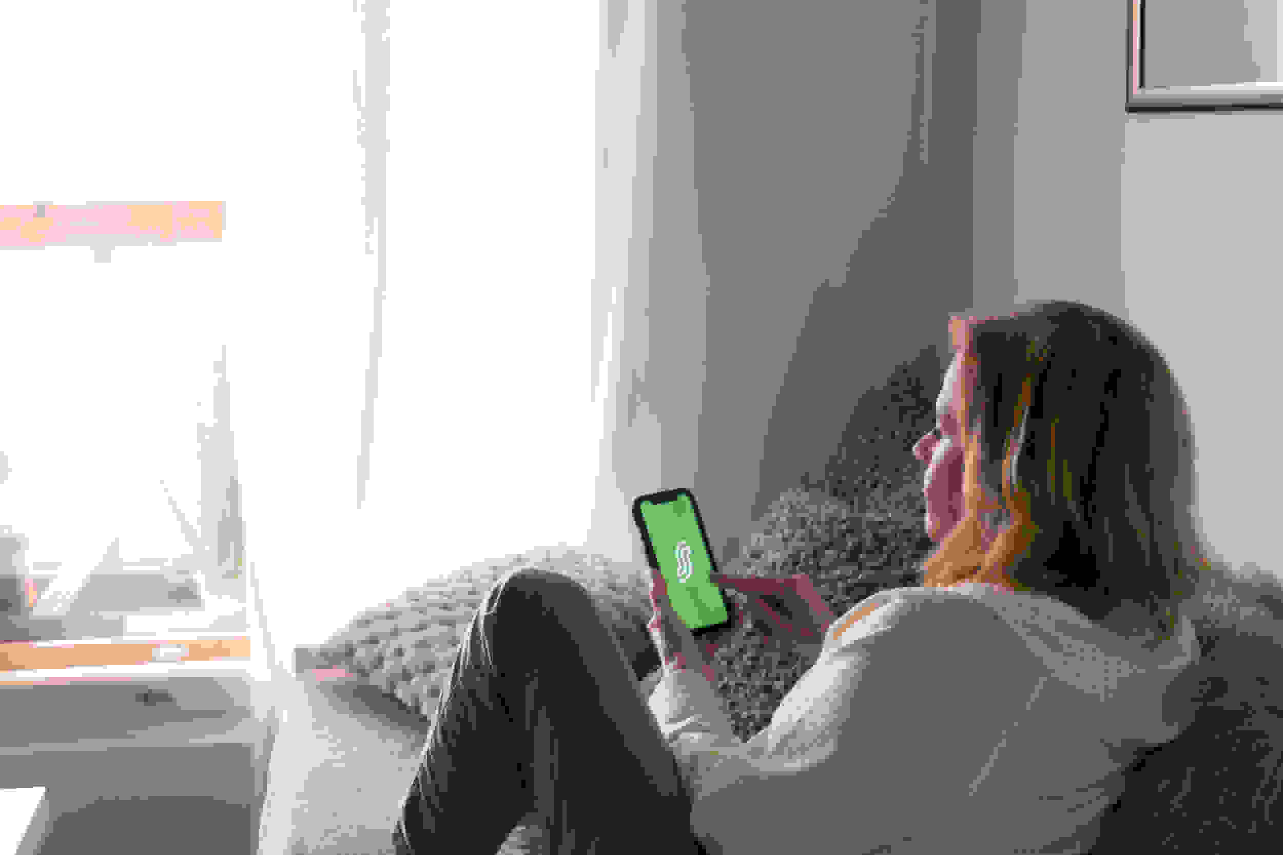 asiakas sohvalla puhelin kädessä