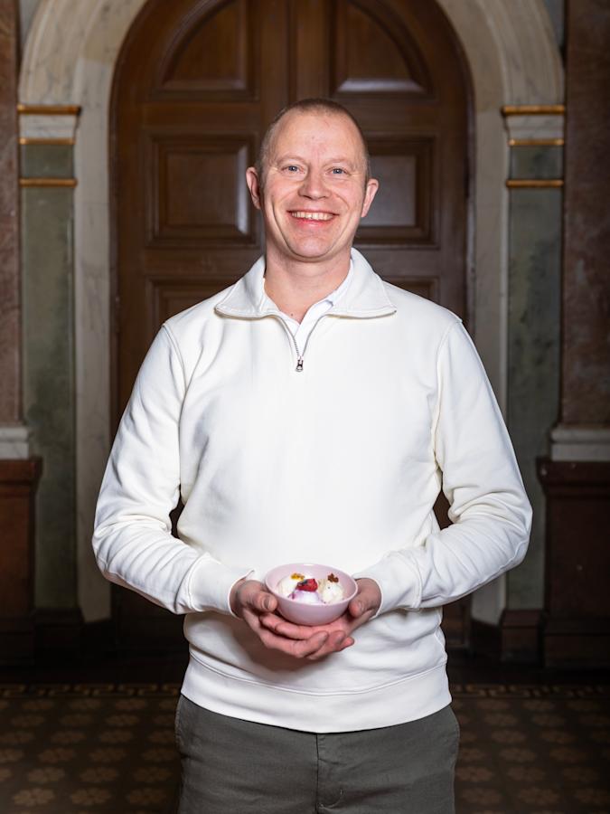 Samuli Wirgentius seisoo ja hymyilee. Kädessä on kuppi jäätelöä.