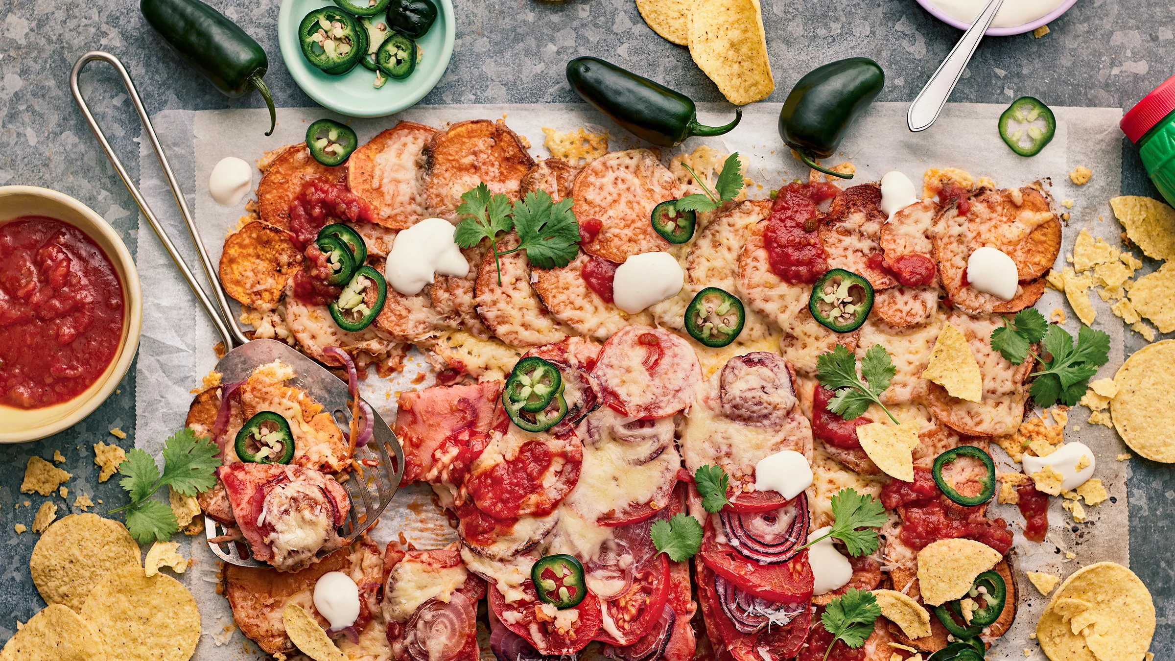 Texmex-uunimakkara bataatilla leivinpaperin päällä korianterilla ja jalapenoilla koristeltuna.