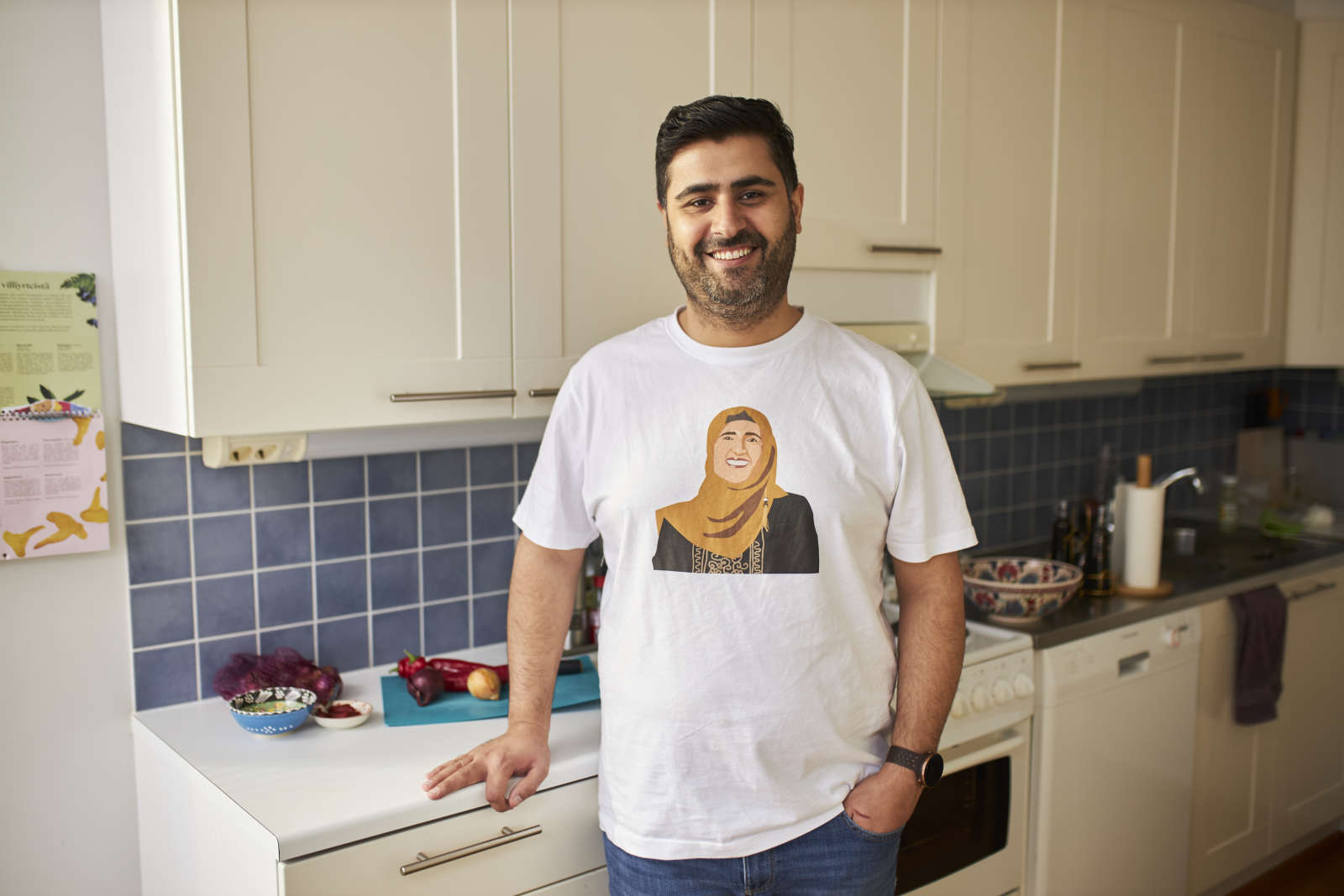 Siva Parlar seisoo keittiössään. Sivalla on t-paita, jossa on hänen äitinsä kuva.