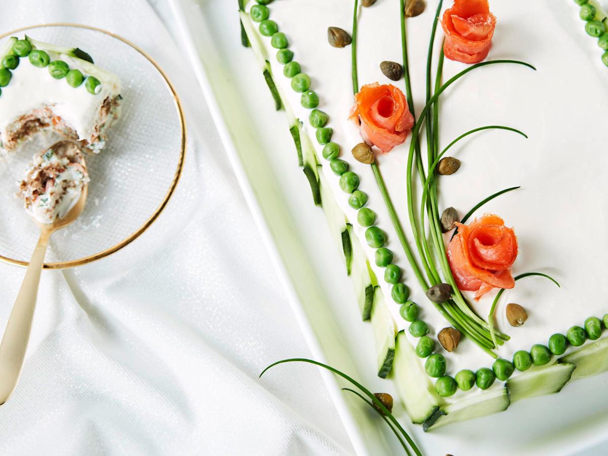 Kehystä kakun päällys sulaneilla pakasteherneillä. Pyöräytä kylmäsavulohiviipaleista ruusukkeita. Sommittele ruohosipulin varsista ja lohiruusuista kukkia kakun pinnalle. Lisää kapriksia nupuiksi.