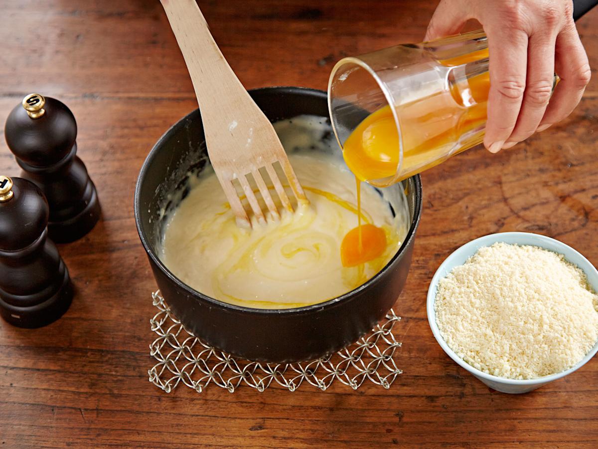 Sekoita kastikkeeseen keltuaiset yksi kerrallaan. Mausta. Lisää juustoraaste.