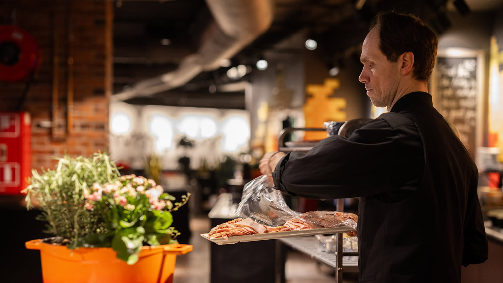 Petri Oramaa kattaa hotellin aamupalapöytään leikkeletarjotinta.