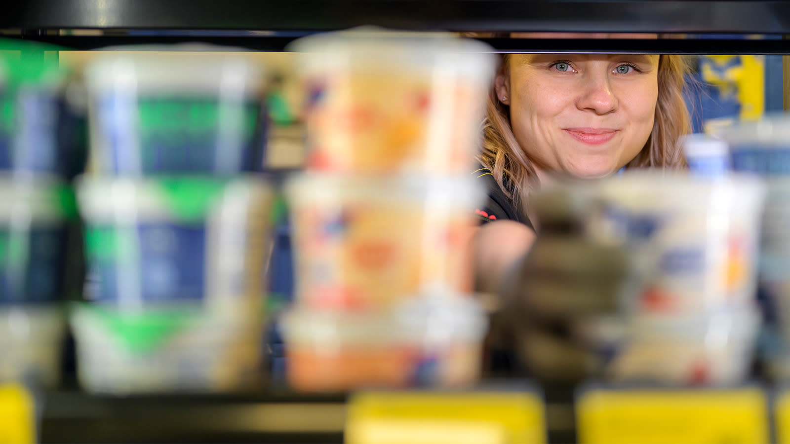 Kati Kuuliainen kurkistaa maitotuotteiden takaa.