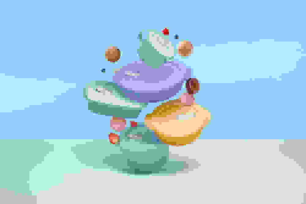 Muovisia Tupperware-astioita ja -rasioita sekä mansikoita ja macaron-leivoksi lentää ilmassa sinistä taustaa vasten.