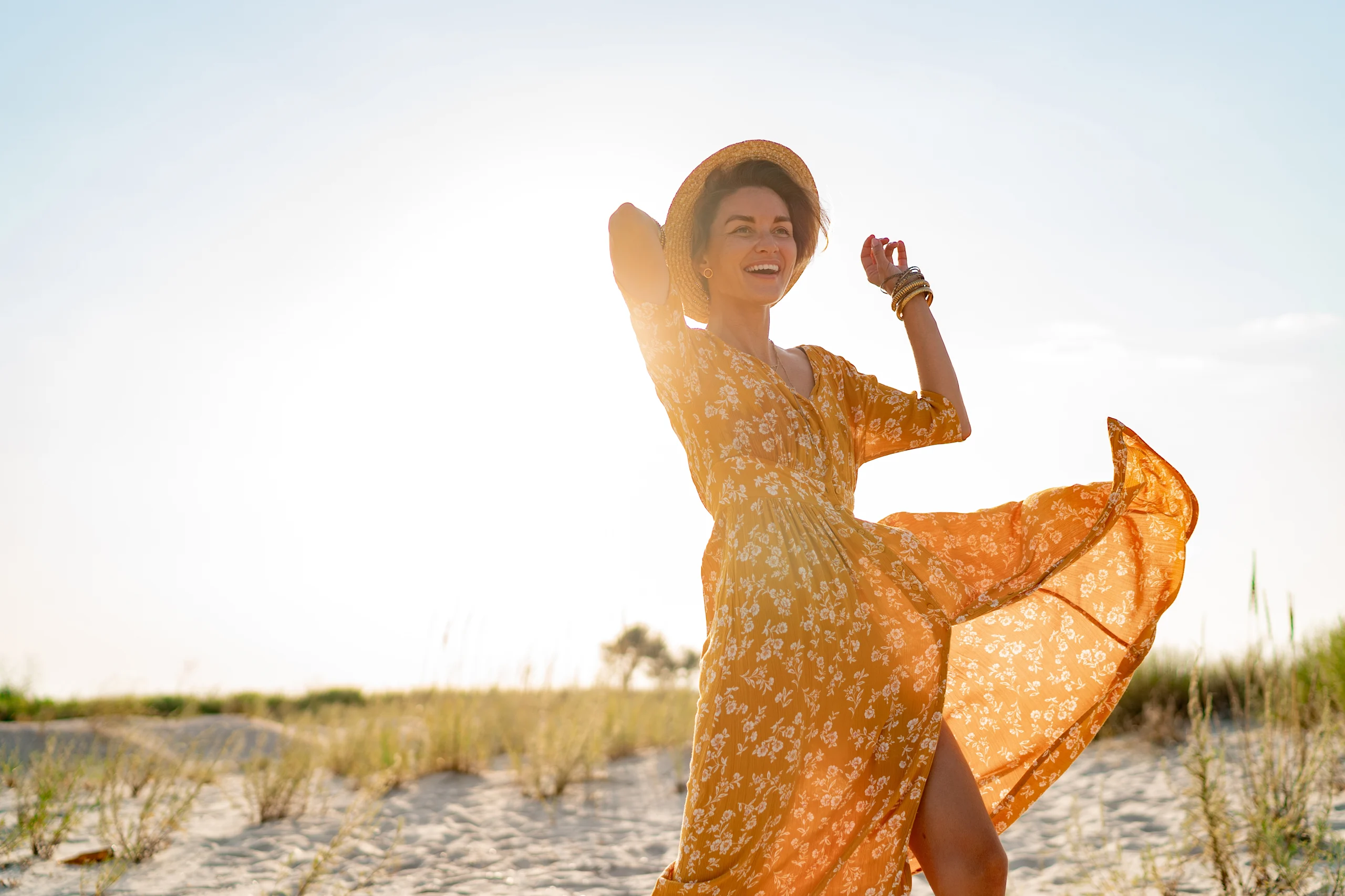 Iloinen nainen keltaisessa kesämekossa auringossa