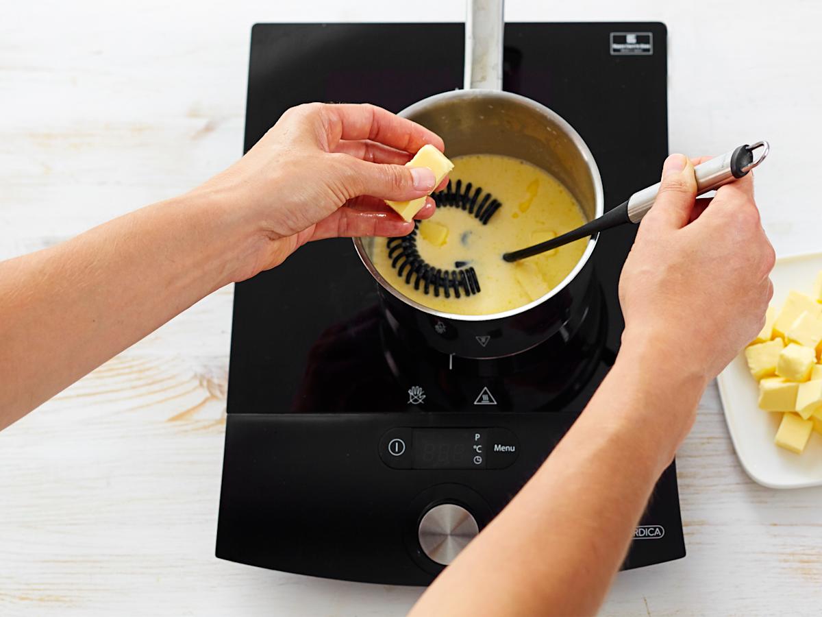 Ota kattila syrjään ja vatkaa joukkoon kylmä voi pieninä kuutioina. Lämmitä ja mausta.