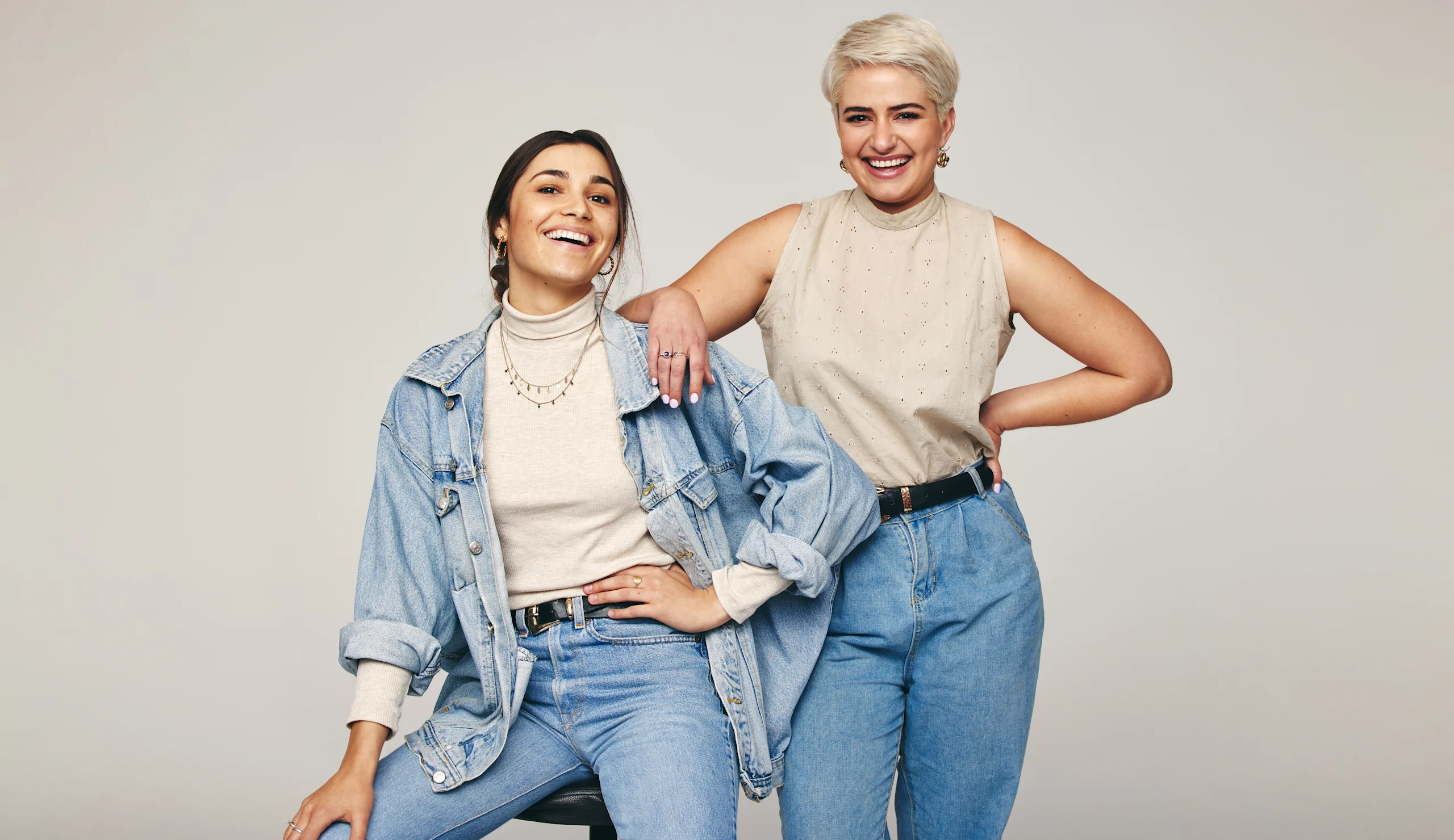 Kaksi naista poseeraa farkut jalassa