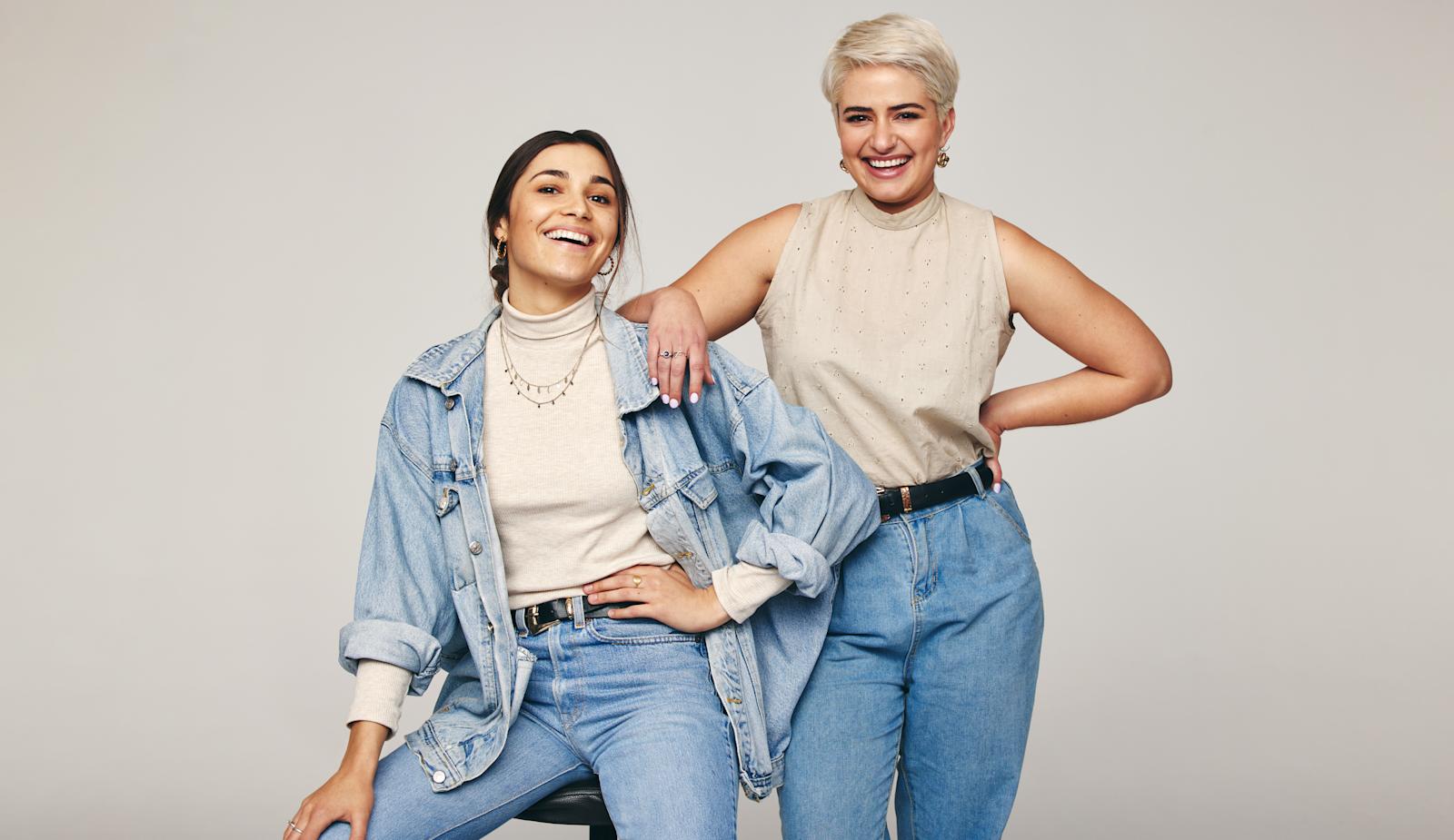 Kaksi naista poseeraa farkut jalassa