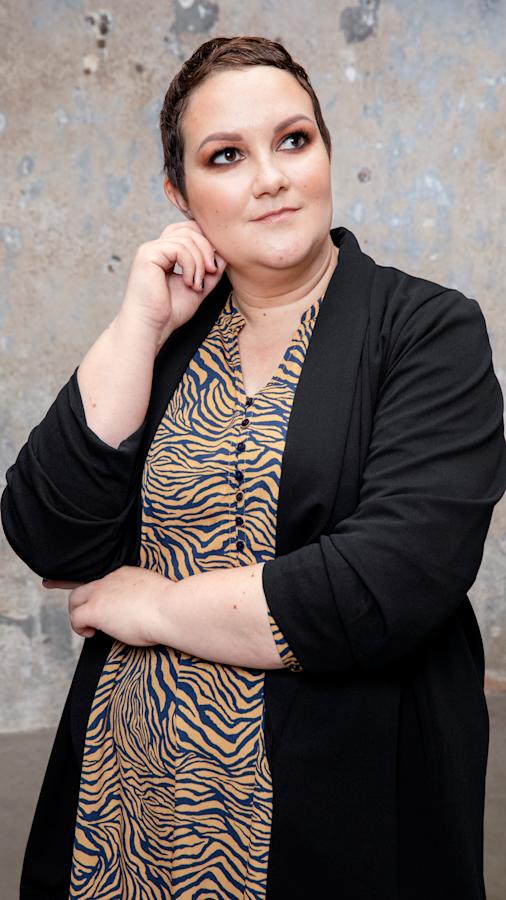 Puolikuva Sannasta, joka on pukeutunut kuviolliseen mekkoon ja jakkuun.