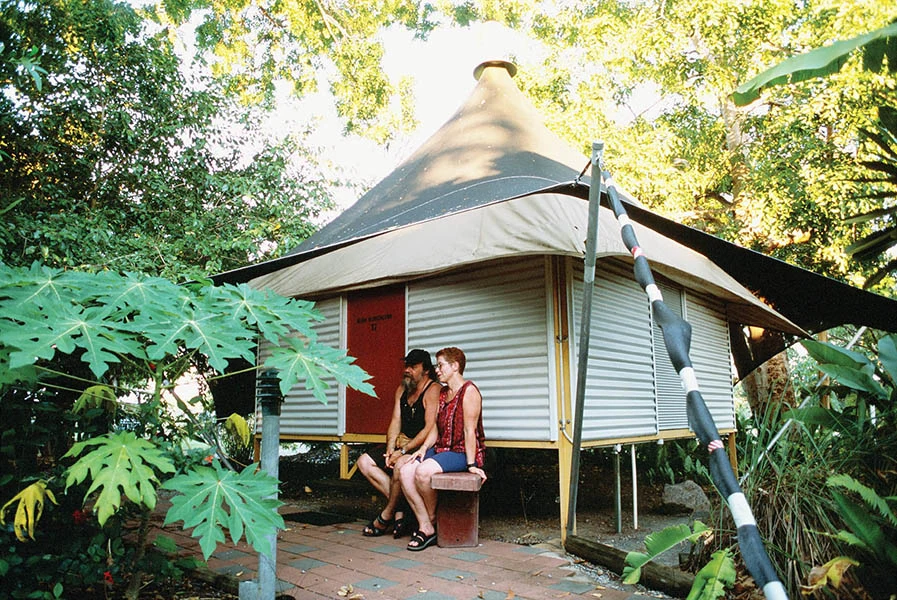A couple sitting in front of Anbinik Kakadu Resort bungalows, NT © Kakadu Cultural Tours