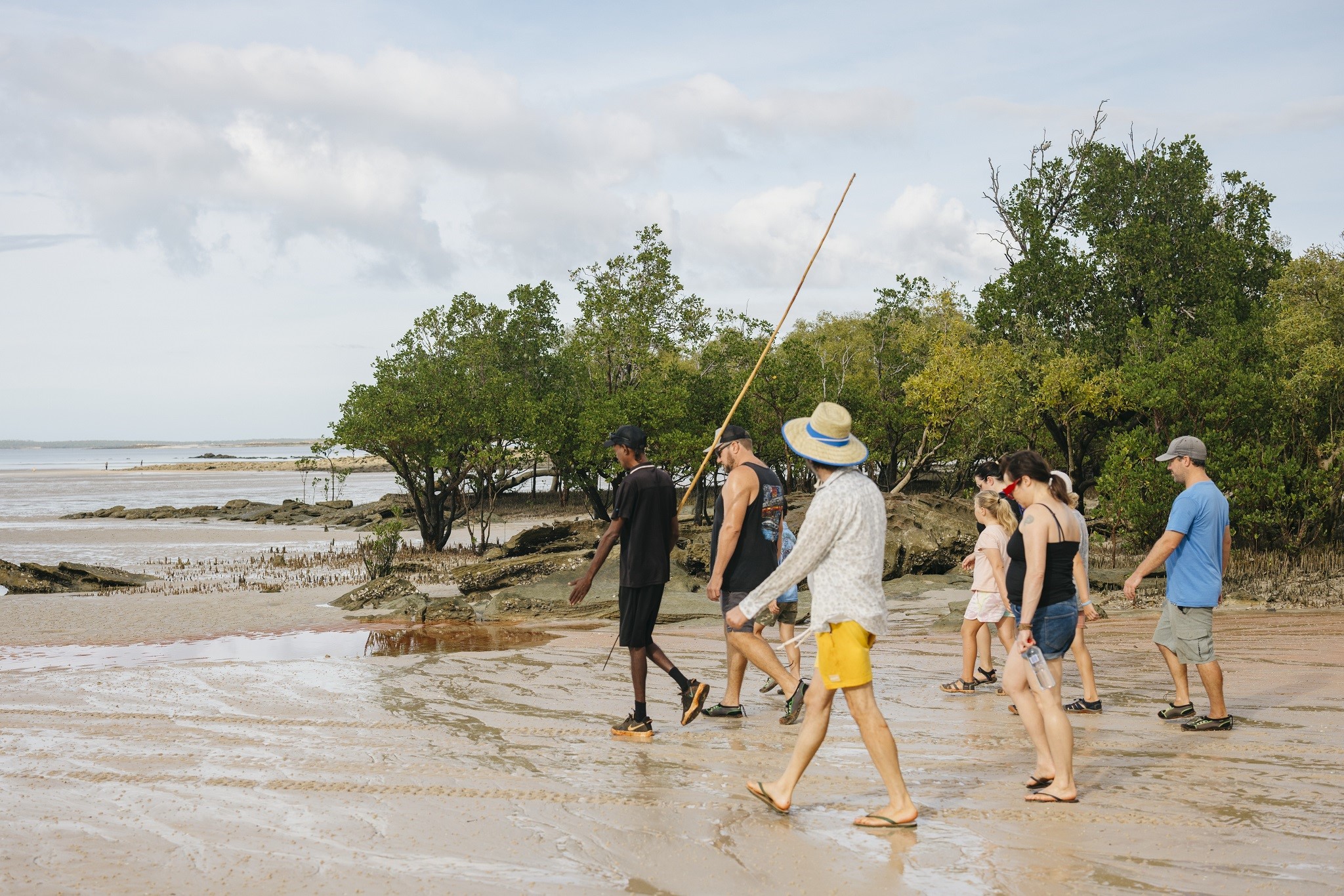 Borrgoron Coast to Creek Tours guide walking on beach with guests at Cygnet Bay, WA © Tourism Australia