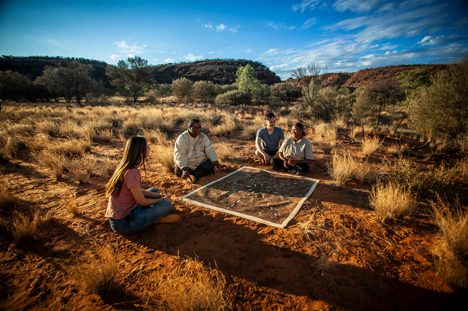  Guides sitting with couple in the outback on a Karrke Aboriginal Cultural Experience & Tours experience, NT © Tourism Australia 