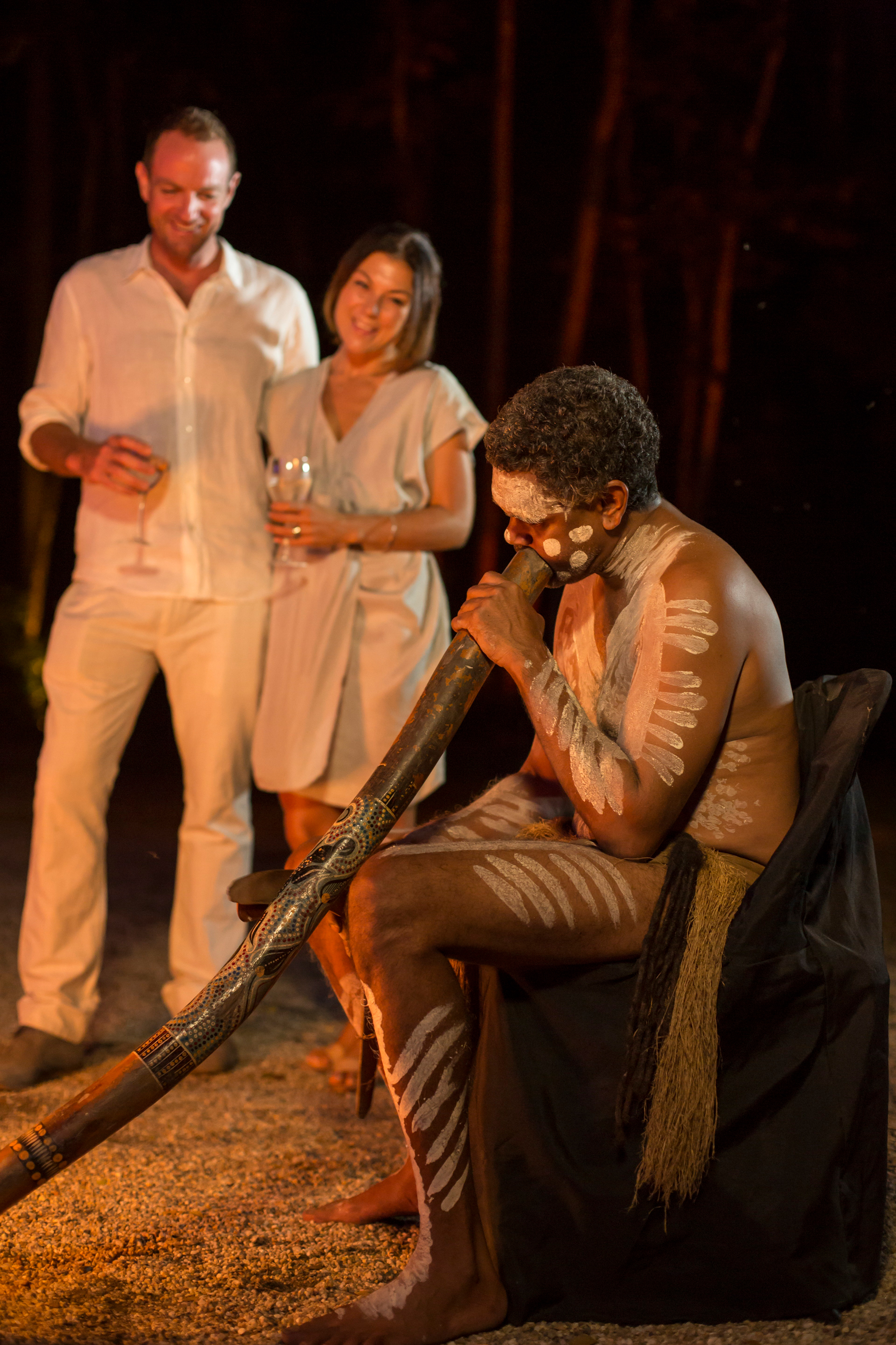 Guests enjoying a didgeridoo performance at Flames of the Forest, QLD © Tourism Australia 