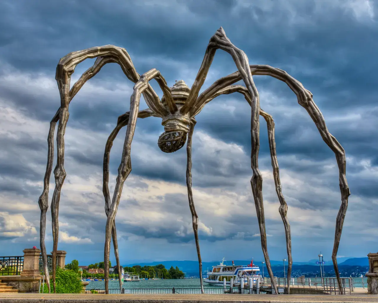 This is a spider statue called "Maman" made by an artist named Louise Bourgeois. She made it to show how spiders and mothers have things in common, like taking care of their babies. If we watch bugs, plants, and animals, we can learn amazing things. 