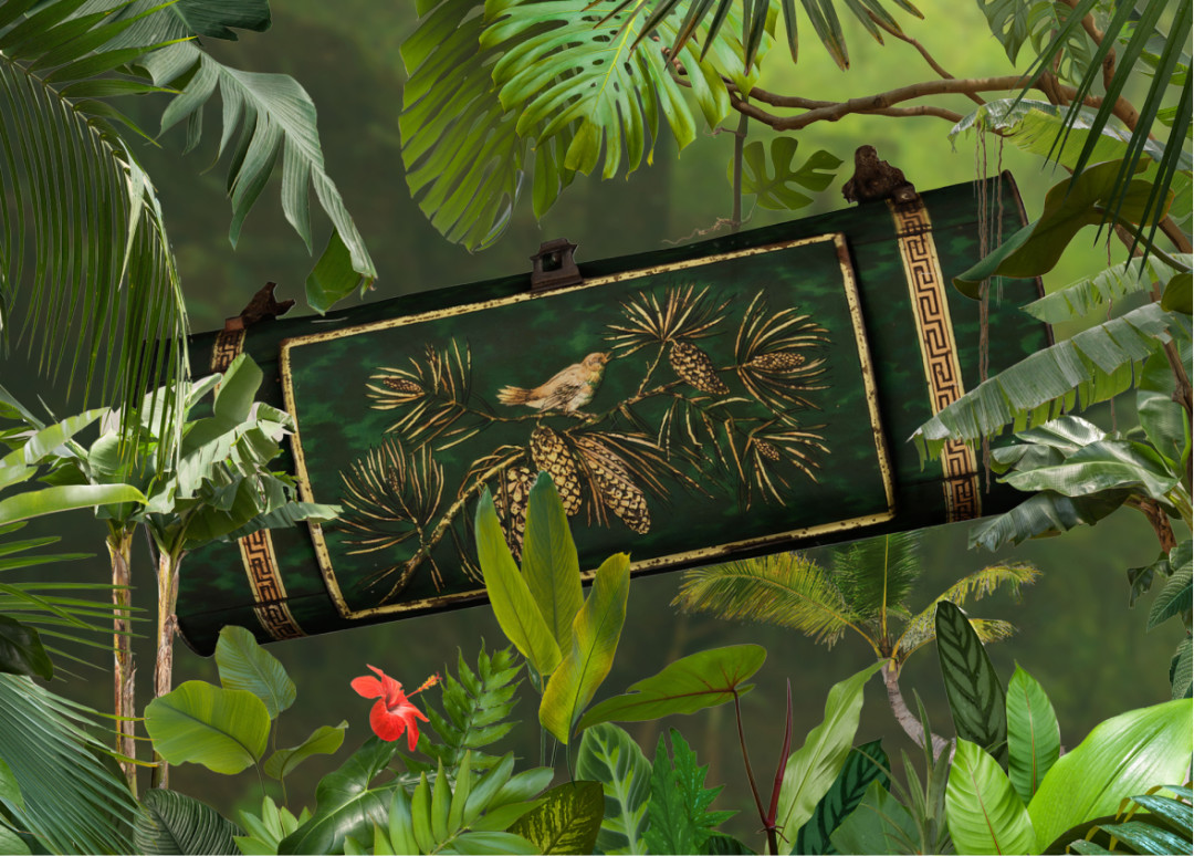 A green botanical box, also called vasculum, with a gold design of a bird sitting on a pine tree. The vasculum is surrounded by exotic plants and flowers.