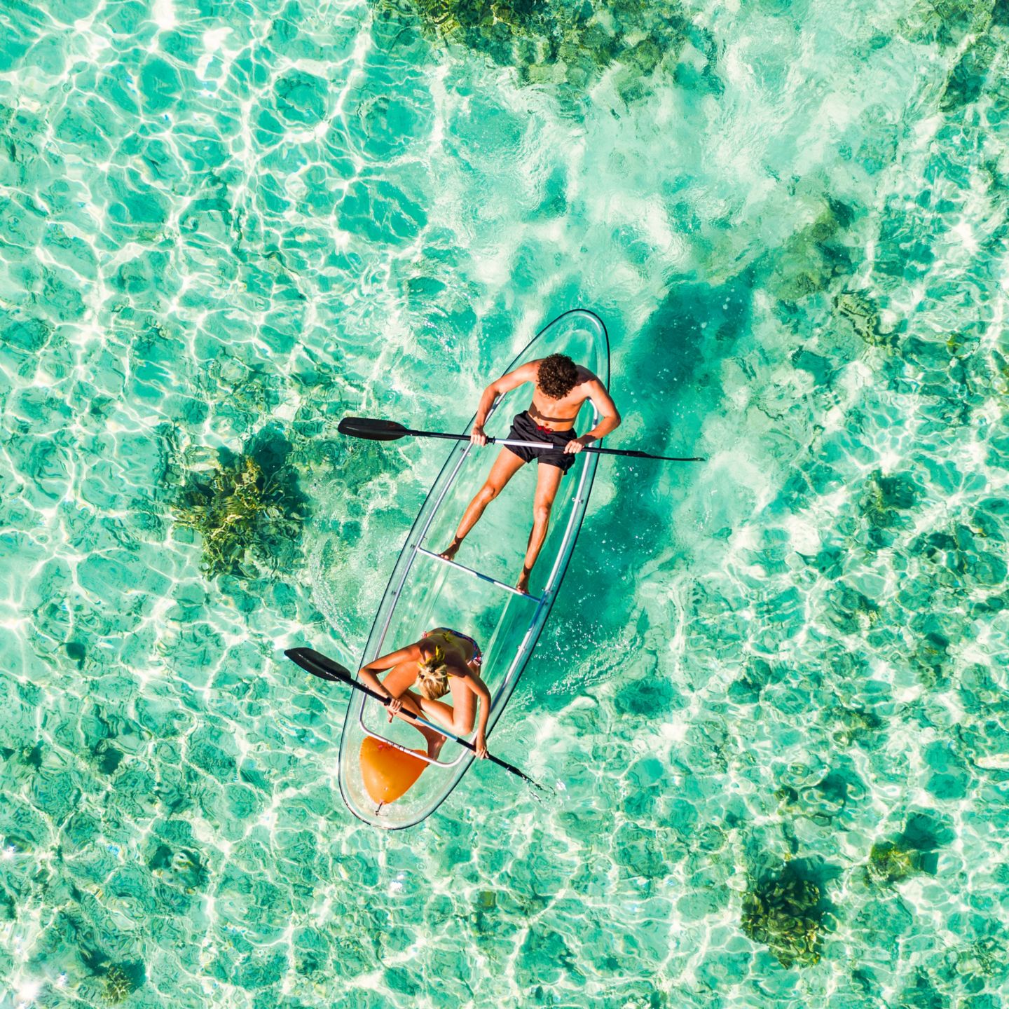 Couple padding on a kayak in the Maldives.