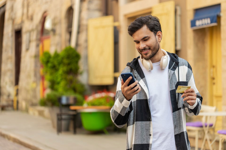 A man looking at a mobile phone while walking down the street
