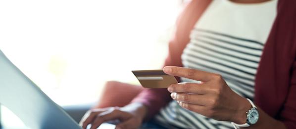 A woman using a laptop computer while holding a credit card