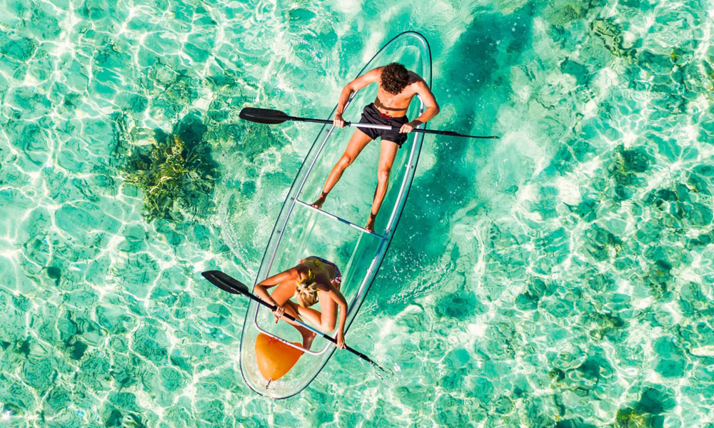 Couple padding on a kayak in the Maldives.