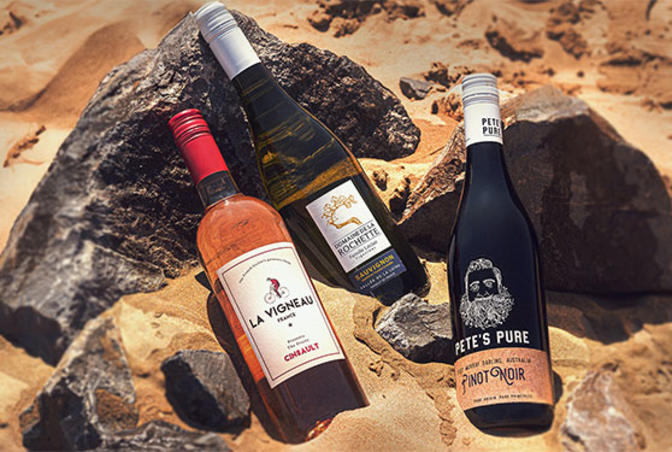 Three bottles of wine layed on a rock on the beach