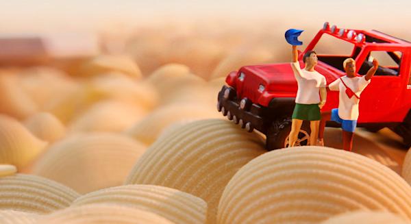Two mini figures beside a jeep waving in the desert made of pasta
