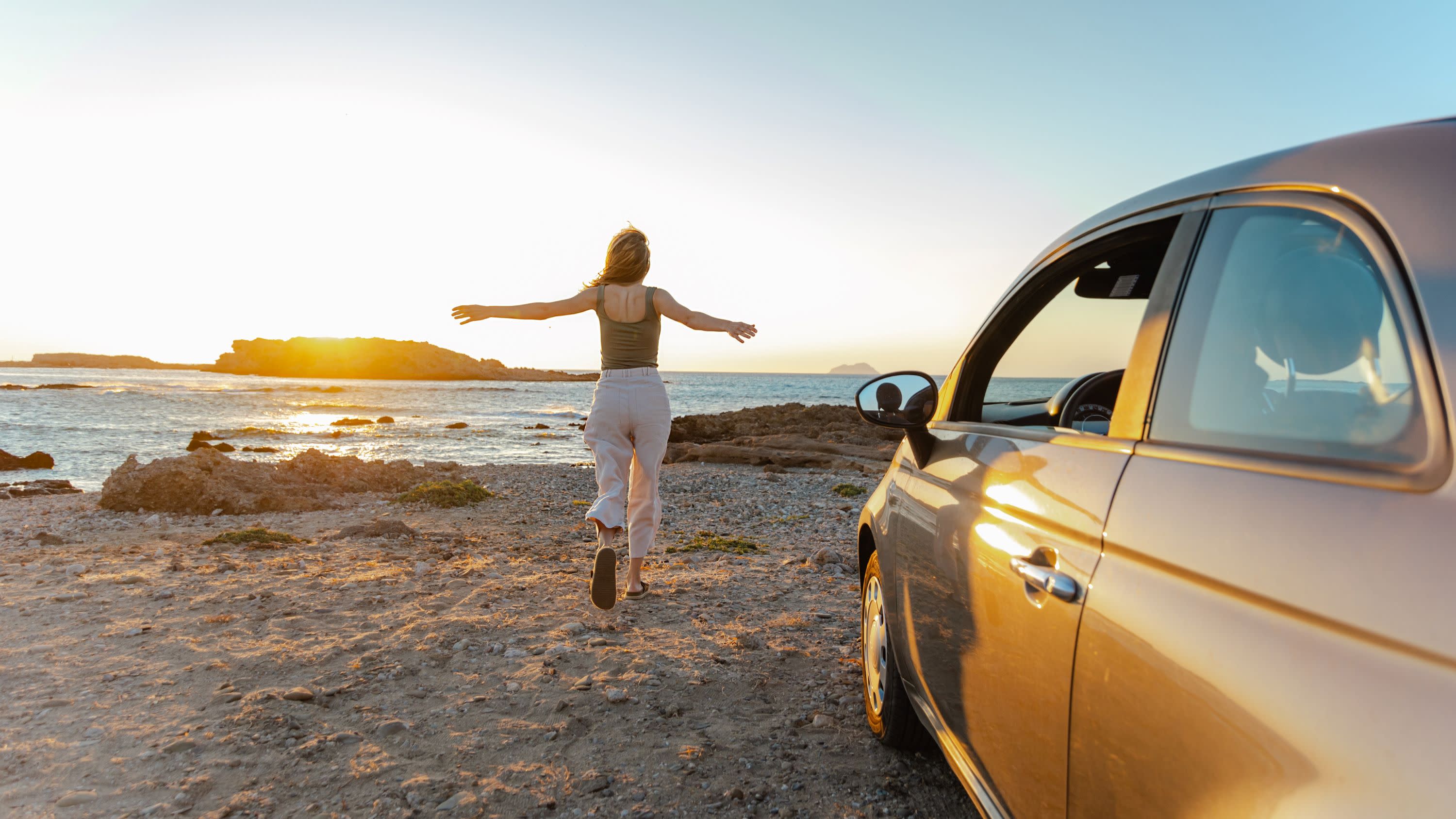 Woman on the beach by a car.